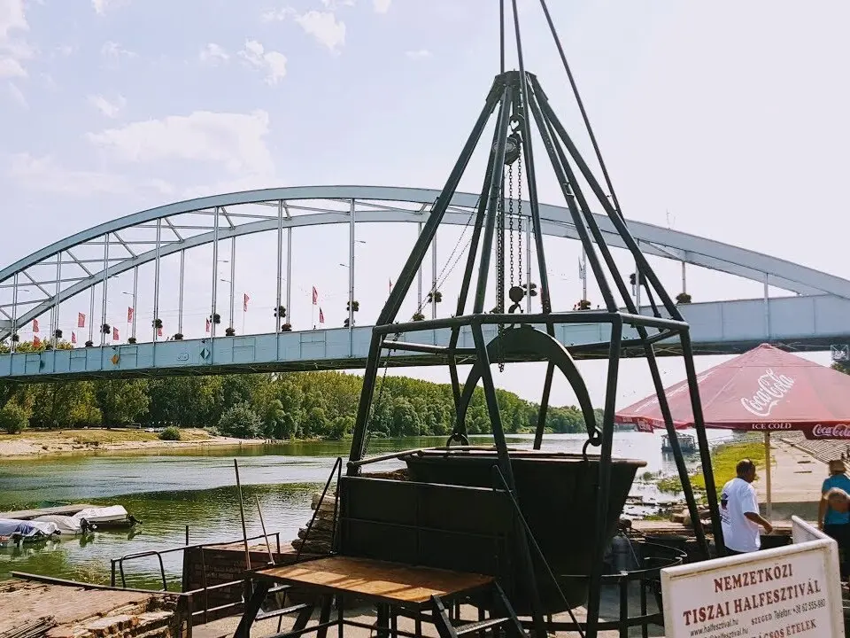A Szegedi halászléfőző verseny nagy bográcsa, háttérben a Belvárosi Híddal